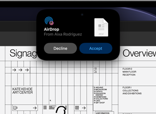 La pantalla muestra la Dynamic Island con una petición de AirDrop en una ventana pequeña sobre un archivo abierto de Adobe Acrobat