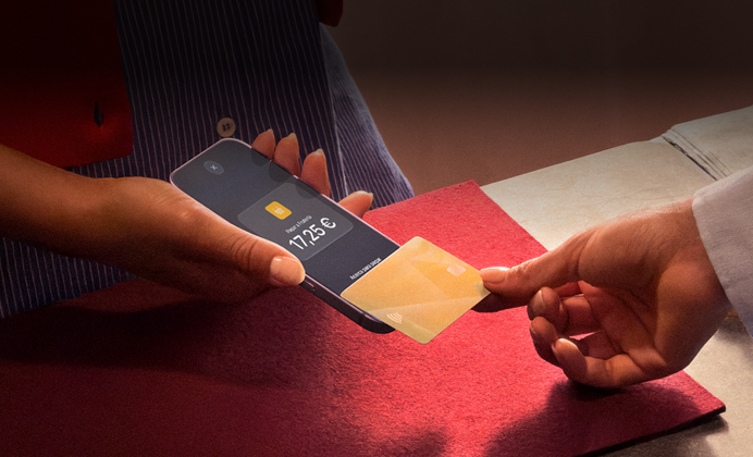 Una mano acerca una tarjeta de crédito a un iPhone para pagar una compra