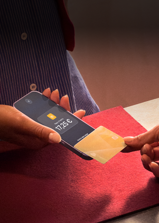 Una mano acerca una tarjeta de crédito a un iPhone para pagar una compra