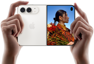 iPhone Duo, color blanco estelar, sujetado por dos manos en horizontal, abierto. Izquierda: sistema de cámaras traseras dual Fusion de 48 Mpx. Derecha: una persona siendo fotografiada en la pantalla exterior. La persona fotografiada puede verse en la pantalla con Duo Preview mientras le hacen la foto.